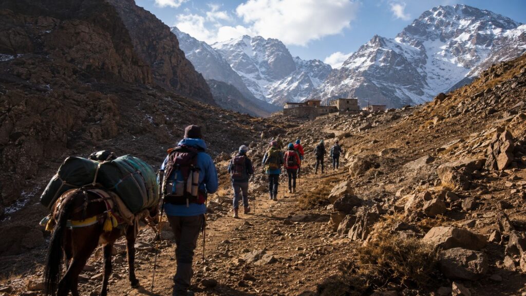 Hikers and a loaded mule trekking through the Atlas Mountains toward Imlil